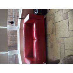 Two seater red faux leather sofa