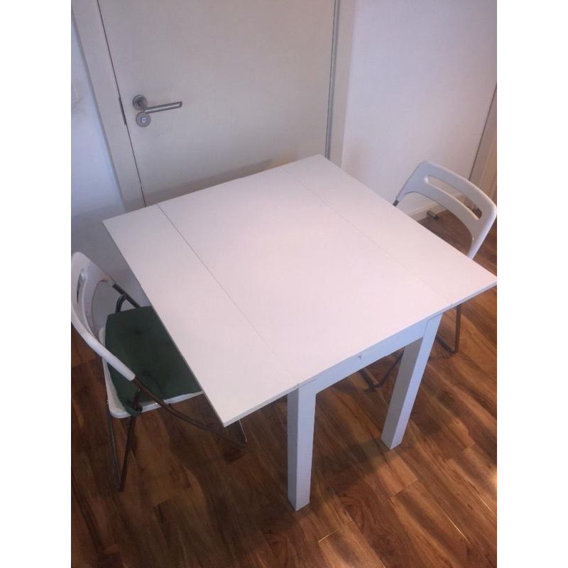 White dining table and two folding chairs